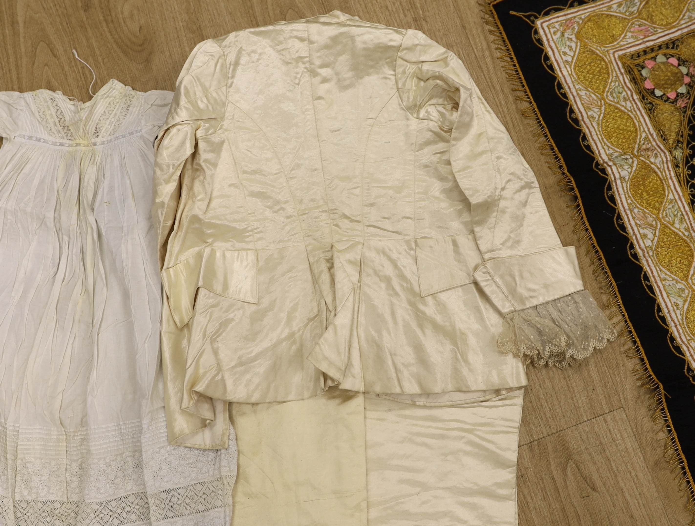 An embroidered Indian felt cover, a cream satin pageboy outfit, a white work christening gown, a silk shawl, a knitted silk shawl and a length of brocade